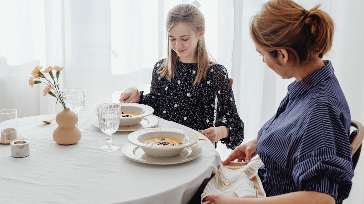 A serene scene of a mother and daughter dining together in a bright, cozy setting.